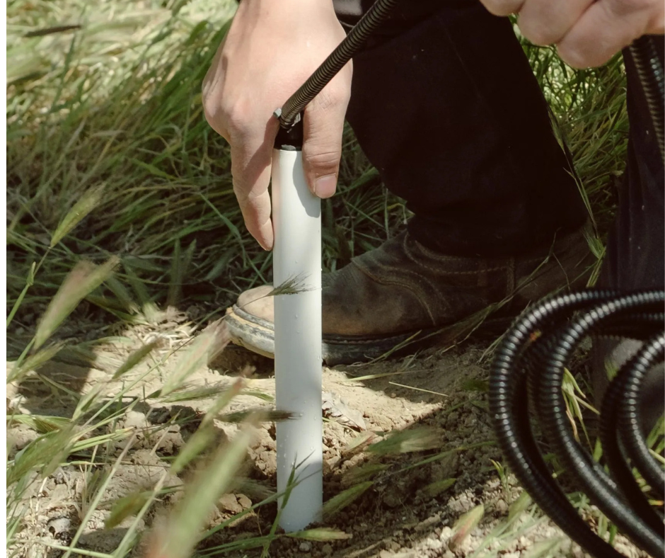 A hand installing a soil moisture probe in the ground