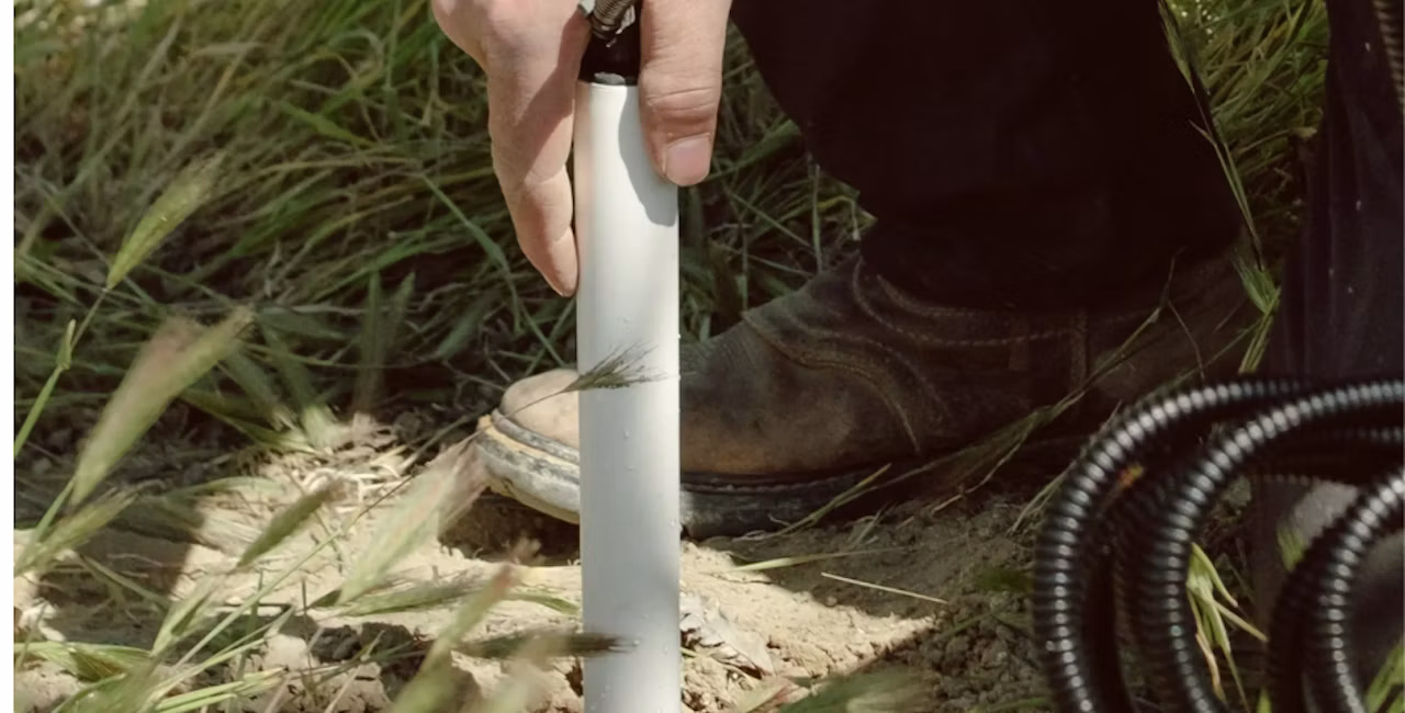 A hand installing a soil moisture probe in the ground