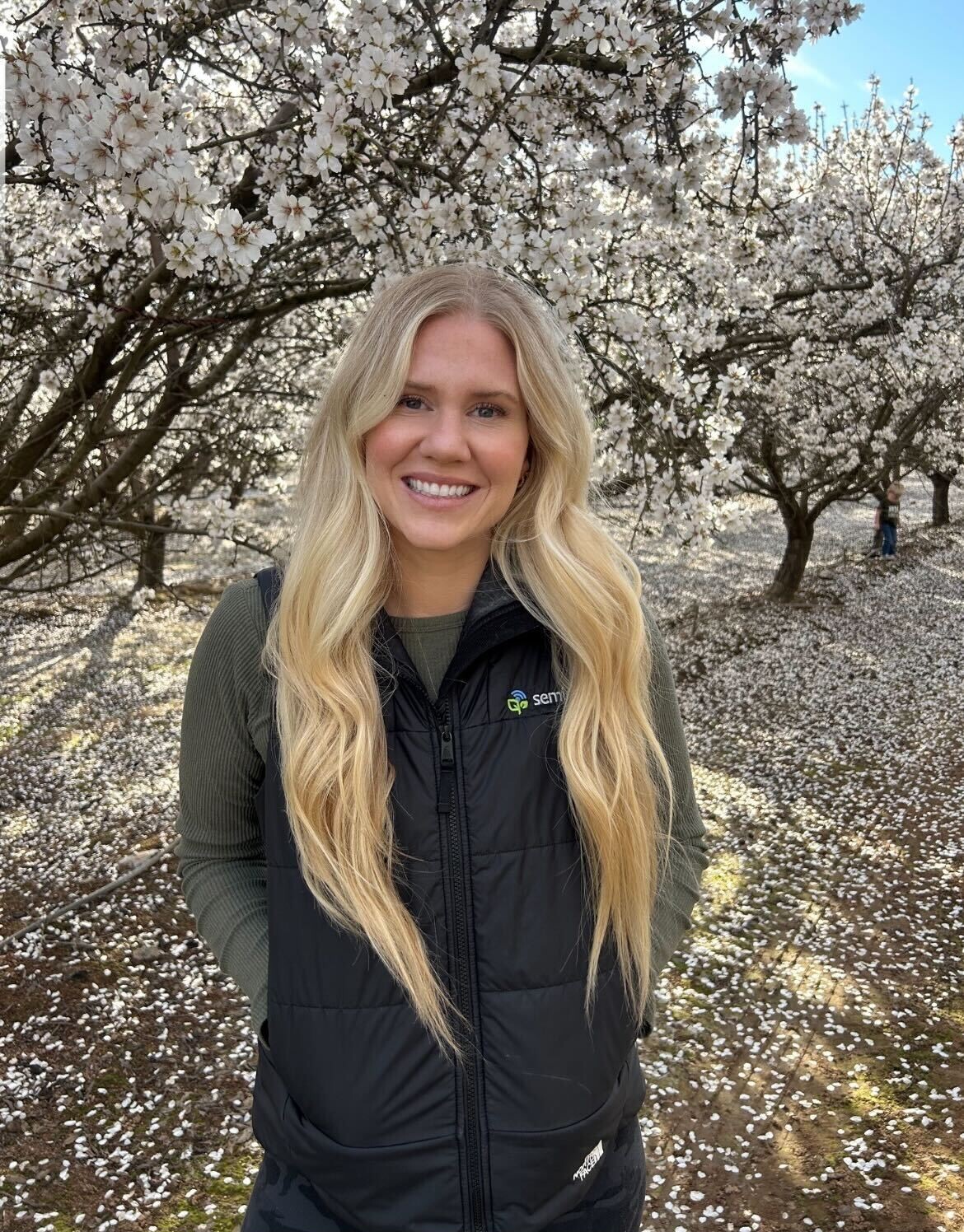 Sydnee standing in an almond orchard during bloom
